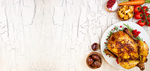 Cooked chicken for Thanksgiving Day. Roasted whole chicken or turkey with autumnal vegetables and fruits for thanksgiving on wooden table. Banner format with copy space