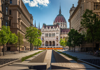Budapest, Hungary - The Memorial of National Unity in Alkotmany street and Parliament of Hungary with traditional yellow tram on a sunny summer day with blue sky and clouds