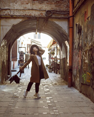 Fototapeta na wymiar woman in stylish coat and hat walking by small european street