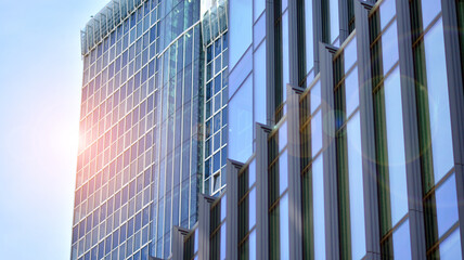 Fototapeta na wymiar Modern architecture with sun ray. Glass and steel facade on a bright sunny day with sunbeams on the blue sky. Economy, finances, business activity concept.