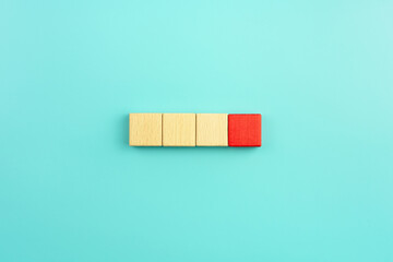 Red wooden block standing out from the group wooden blocks on blue background. Leadership,...
