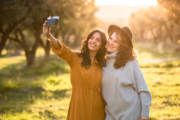 a couple of girls taking a selfie in the field at sunset. lesbian concept