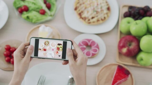 Women use mobile phones to take pictures of food or take live video on social networking applications. Food for lunch looks appetizing. Photography and take picture for review food concepts.