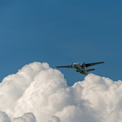 A twin-engine passenger plane with the landing gear retracted after takeoff gaining altitude above the clouds