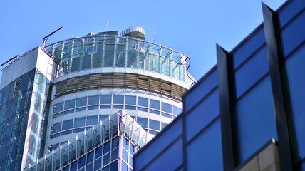 Fototapeta premium Modern architecture with sun ray. Glass and steel facade on a bright sunny day with sunbeams on the blue sky. Economy, finances, business activity concept.
