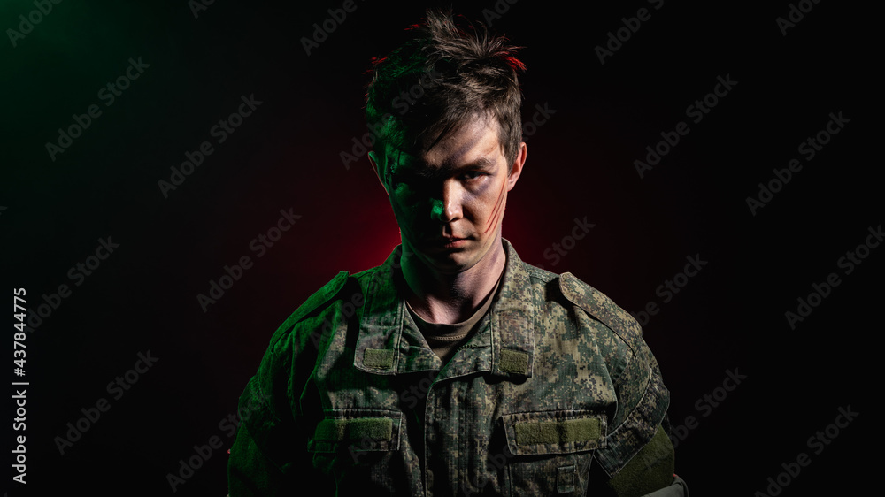 Wall mural A close-up portrait of a soldier in scars and battle paint, illuminated by green light against a backdrop of red smoke