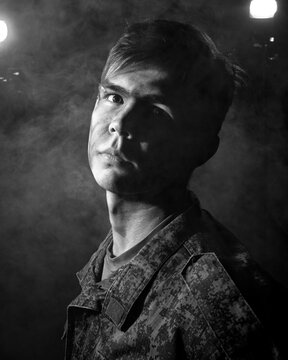 Black white portrait of a young soldier on a black background with smoke