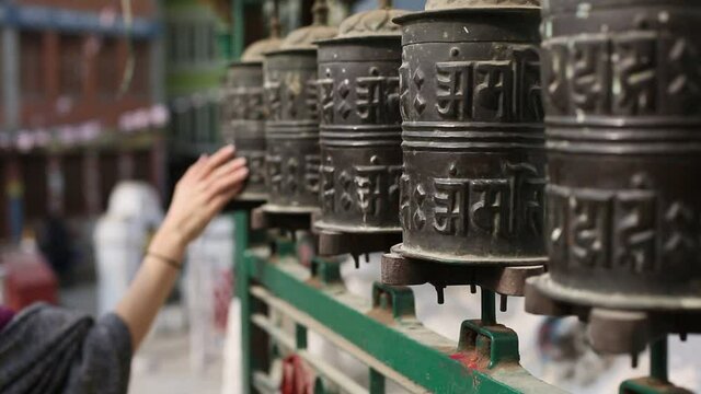 Female hand rotates the Tibetan Prayer wheel