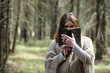 A man in a cassock spends a ritual in a dark forest