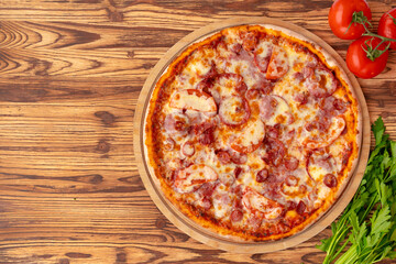 Top view of freshly baked pizza on wooden background