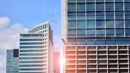 Modern architecture with sun ray. Glass and steel facade on a bright sunny day with sunbeams on the blue sky. Economy, finances, business activity concept.