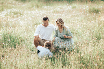 Man, woman and child in the field picking flowers, young family concept