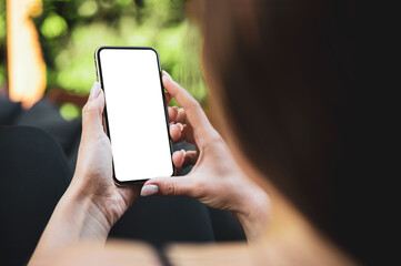 Girl using smartphone blank screen frameless modern design while lying on the sofa in garden