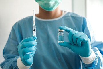 Close up doctor's hand holding medicine bottle and syringe for vaccine to patient on blue...