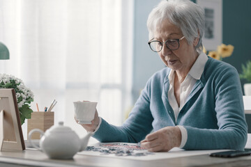 Senior woman sitting at desk and solving a puzzle