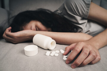 Woman taking medicine overdose and lying on the couch with open pills bottle. overdose and suicide...