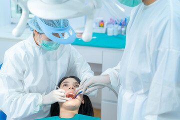 Dentist in lab coat due to Covid 19, check patient's teeth at dental - Powered by Adobe