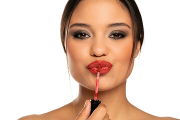 Portrait of a young beautiful woman applies lip gloss