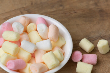 Candy junk food in a white bowl blurry wood background.