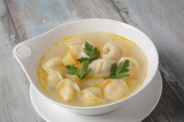 Soup with pelmeni (russian dumplings). Soup with meat dumplings, potatoes and other vegetables
