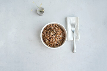 Bowl of buckwheat on a grey concrete background in minimalistic style. Concept of healthy food.