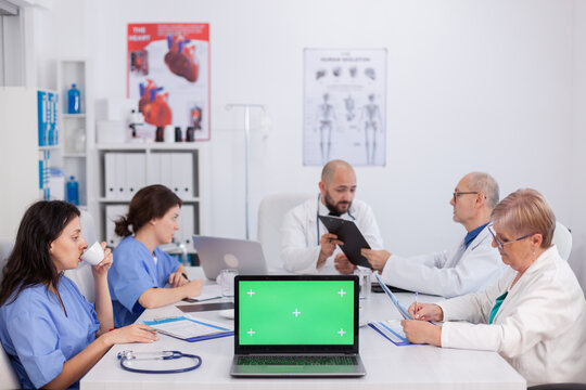 Mock up green screen chroma key laptop computer with isolated display standing on desk in conference meeting room. Doctors teamwork discussing microbiology expertise analyzing disease research - Powered by Adobe