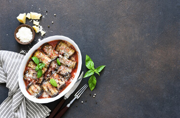 Roll with eggplant and ricotta in tomato juice with parmesan. Baked eggplant with sauce and basil. View from above.