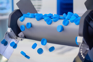 Production line - many blue plastic bottle caps falling from conveyor belt at factory, exhibition. Manufacturing, recycling, industry, technology equipment concept