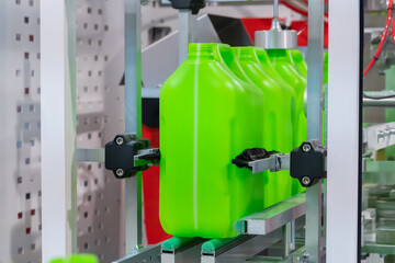 Empty green plastic jerrycans moving on conveyor belt of automatic pet blow molding machine at...