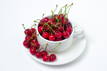 Red cherries in a mug on a white background. Sweet cherry with tails. Healthy food