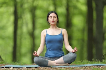 Poster Asian woman doing yoga lotus pose in a forest © Antonioguillem