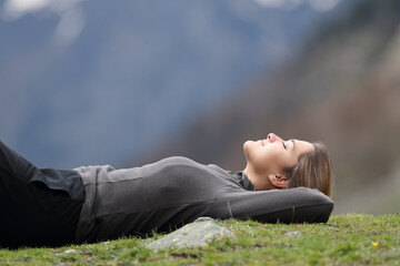 Trekker resting lying on the grass in the mountain