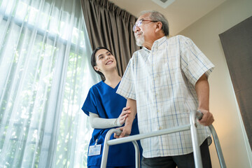 Asian female therapist helping senior male patient to practice walking	
