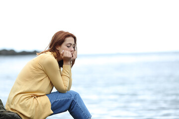 Sad woman thinking alone on the beach