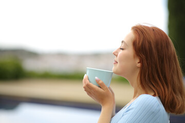 Woman smelling coffee in a terrace at hotel