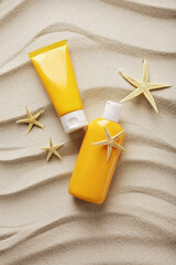 suntan lotion, cosmetic cream on sand beach with seashells