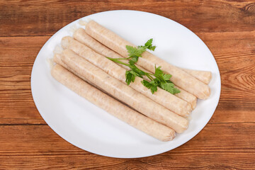 Raw chicken sausages with parsley on dish on rustic table