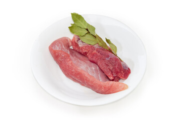 Raw lean pork, dry bay leaves twig on the white dish