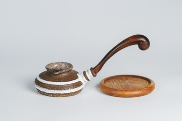 Low and wide brown cezve with woden handle and small wooden coaster on white background. Coffee making concept