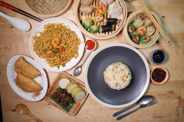 Dumplings dim sum bamboo steamer egg fried rice pulut lemang beef rendang stair fried tofu shrimp noodles chili oil dark soya sauce chpstick fork spoon on wooden table variety cuisine snack fast food