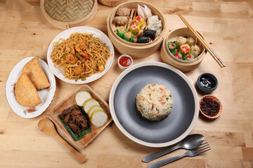 Dumplings dim sum bamboo steamer egg fried rice pulut lemang beef rendang stair fried tofu shrimp noodles chili oil dark soya sauce chpstick fork spoon on wooden table variety cuisine snack fast food