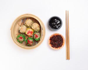 Dumplings dim sum momo variety meat vegetable crab fish seafood sweet savory spicy in wooden bamboo steamer chili oil dark soya sauce chopsticks over white background