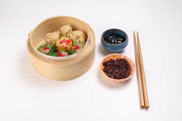 Dumplings dim sum momo variety meat vegetable crab fish seafood sweet savory spicy in wooden bamboo steamer chili oil dark soya sauce chopsticks over white background