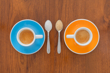 Cups of coffee with spoons on wooden background from top