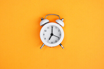 White vintage alarm clock on orange background.
