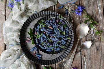 Close-up of a metal bowl full of ripe blue honeysuckle and blueberries