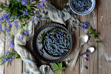 Metal bowls with ripe juicy blue berries on a gray rustic background. Top view