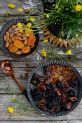 Vertical composition. Dried fruits, nuts and yellow flowers on gray wooden background, top view