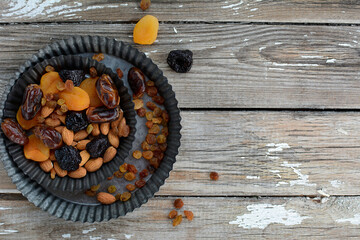 Layout of dried fruits - prunes, dates, raisins, dried apricots and nuts on a gray background. Top view, copy space.