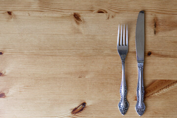 Silver - colored cutlery-knife and fork on a wooden background with a copy of the space